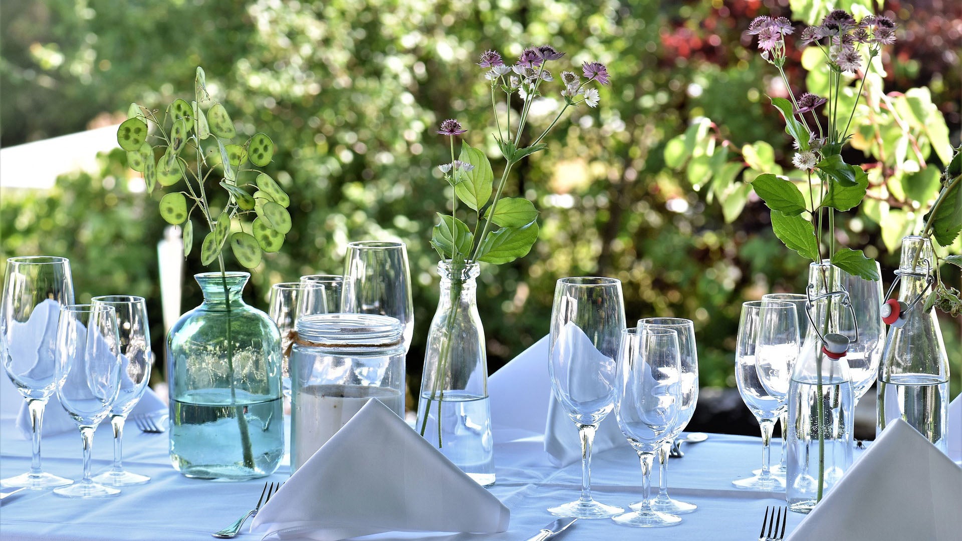 Gedeckter Tisch mit Gläsern, Servietten und Blumen